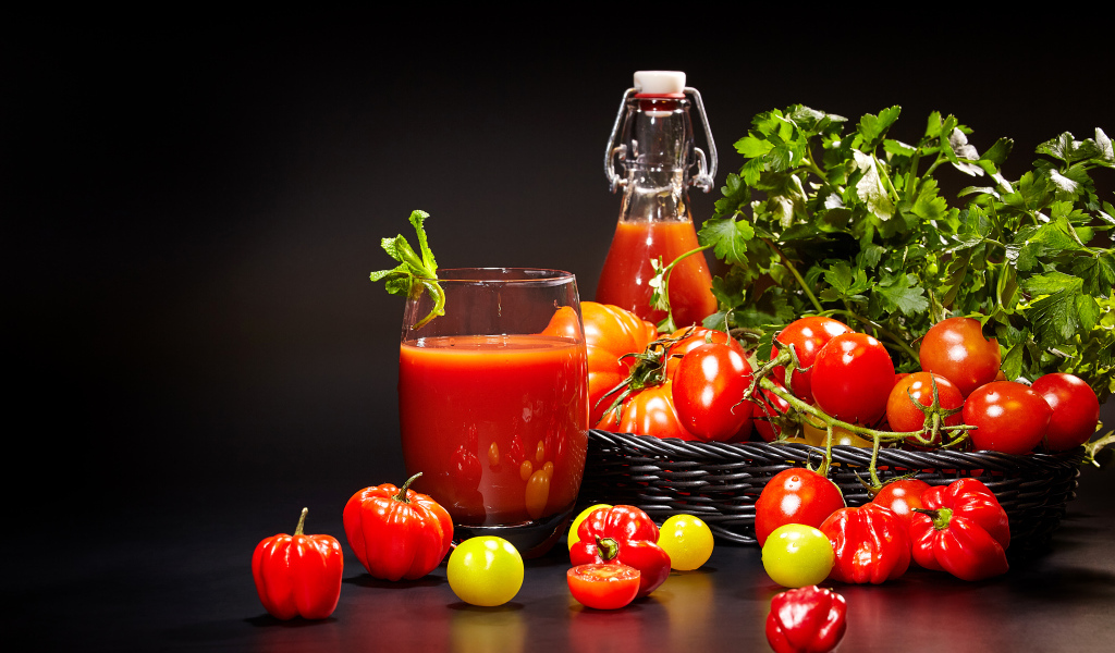 Томатный сок и свежие помидоры на столе на черном фоне