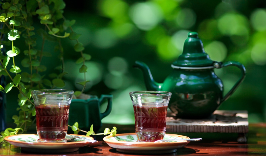 Две чашки чая и зеленый чайник на столе 