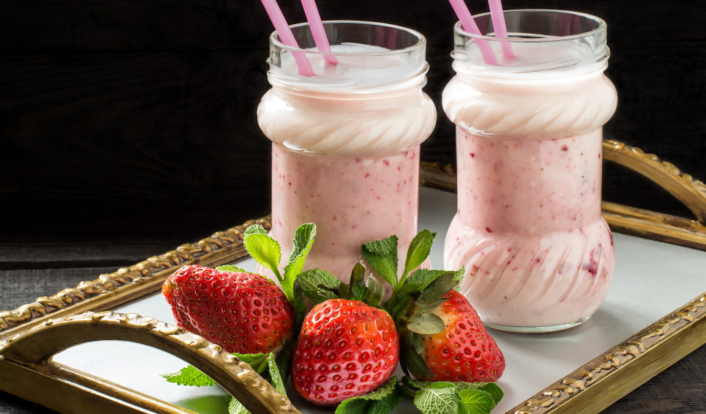 Два свежих клубничных коктейля с трубочками и ягодами клубники