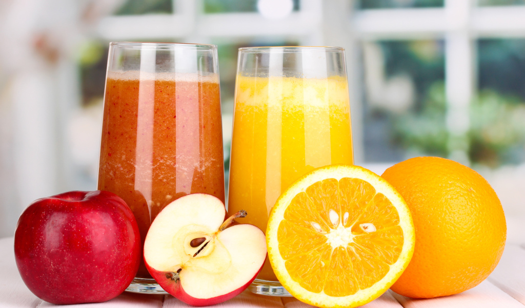 Два стакана с яблочным и апельсиновым соком и свежими фруктами
