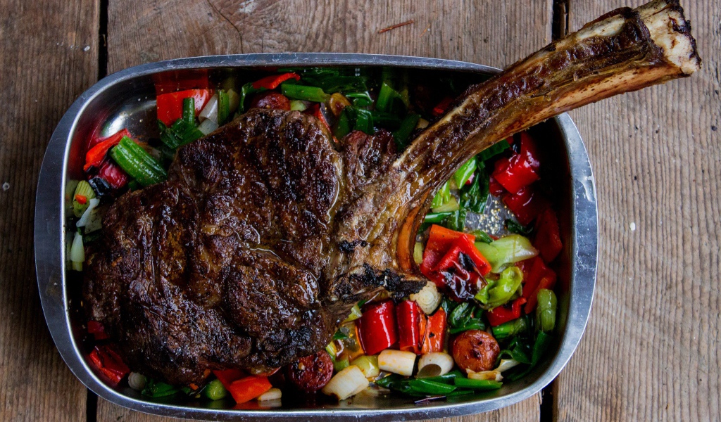 Кусок жареного мяса на ребрышке с овощами