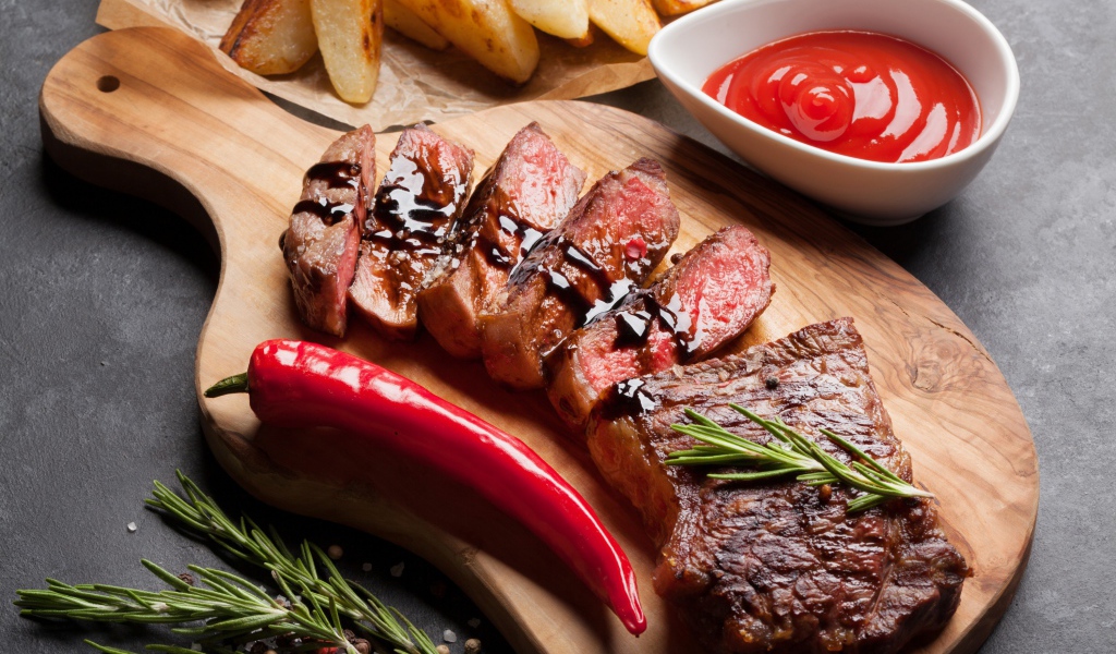 Аппетитный сочный стейк с соусом, красным перцем и специями на столе