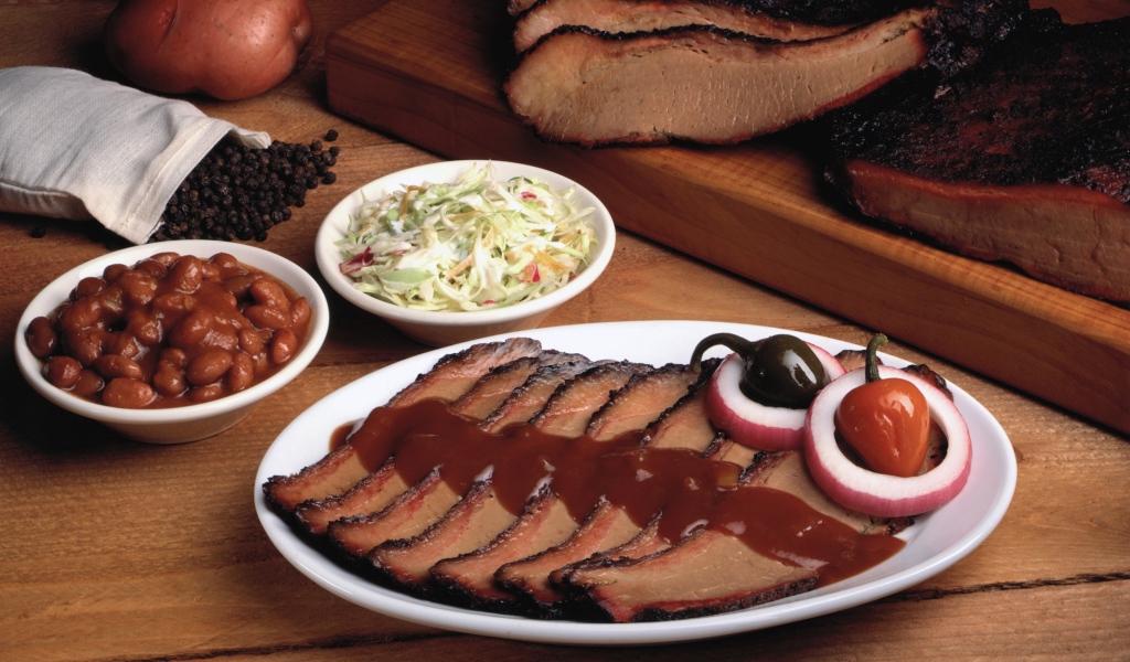 Аппетитные кусочки мяса барбекю на столе с овощами