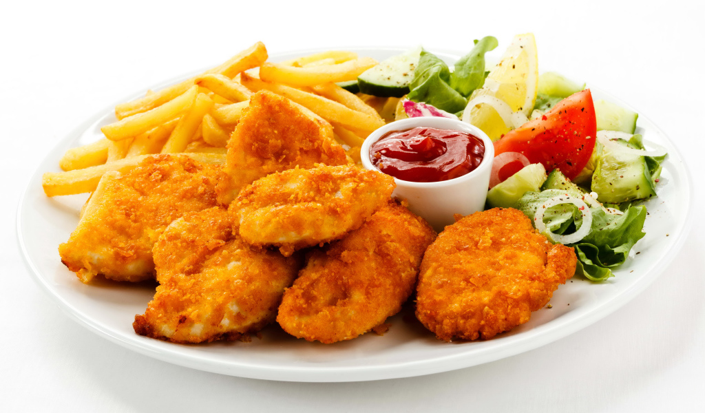 Куриные наггетсы с кетчупом, картофелем фри и салатом на белой тарелке