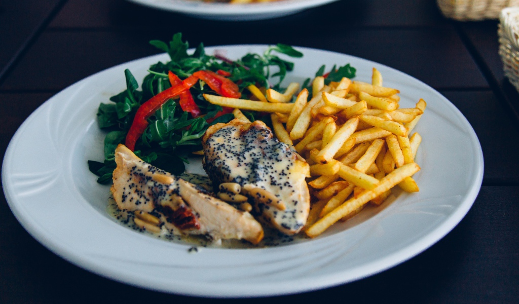 Курица с картофелем фри и салатом на большой белой тарелке