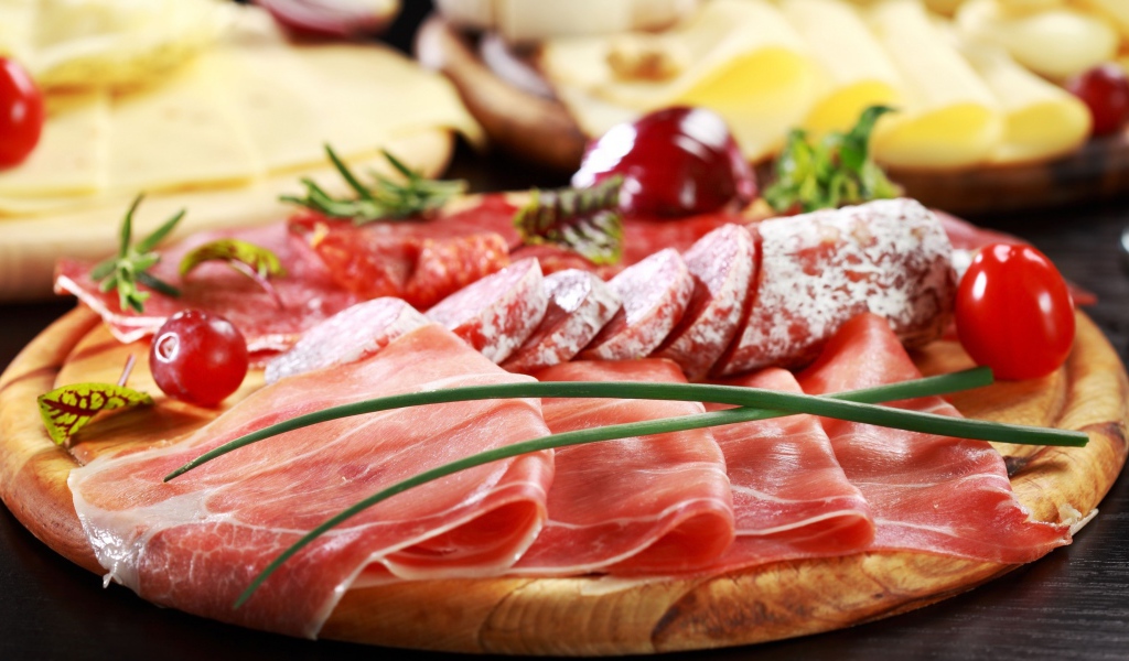 Мясная нарезка на разделочной доске с овощами