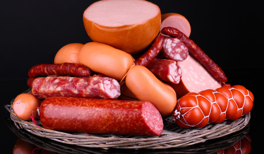 Мясные продукты колбасы и сосиски на черном фоне