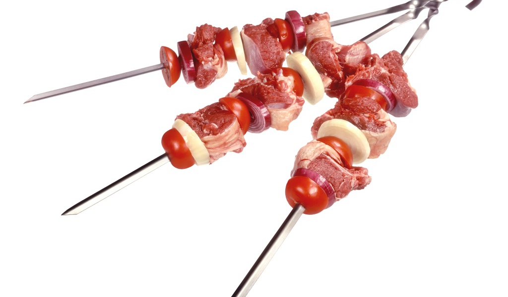 Мясо с овощами для шашлыка на шампурах на белом фоне