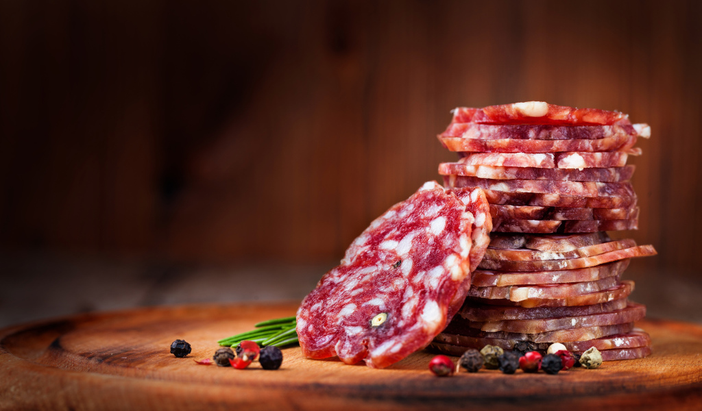 Нарезанная сухая колбаса на столе со специями