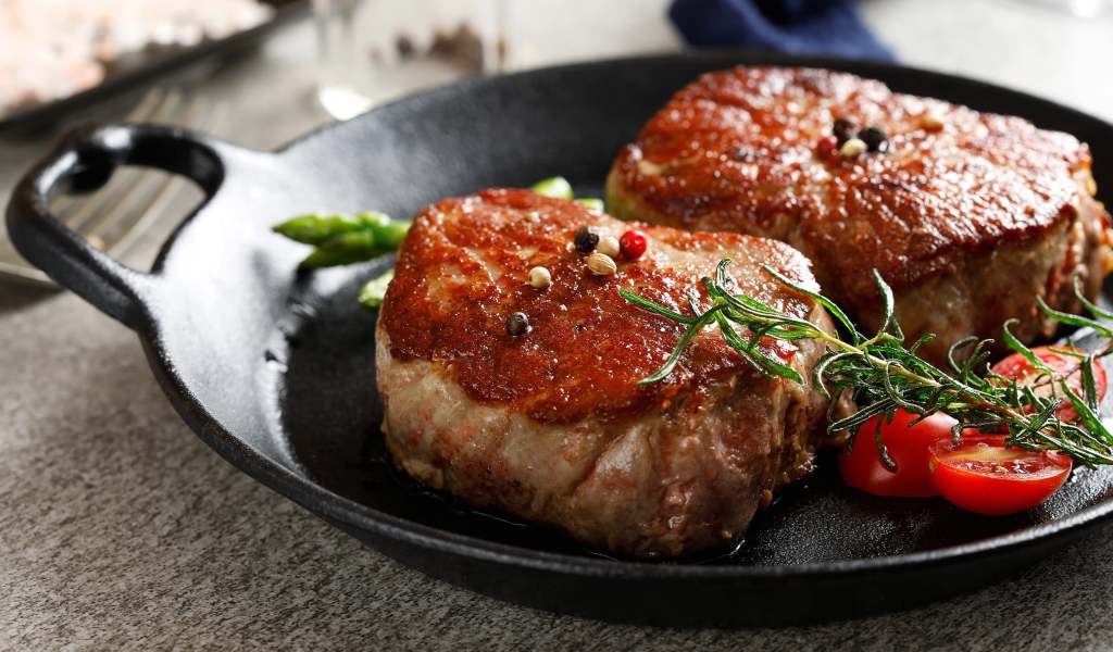 Два аппетитных сочных куска мяса с помидорами и розмарином