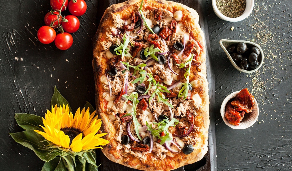 Жареная пицца с мясом на столе с желтым цветком подсолнуха