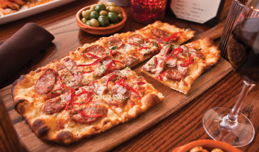 Порезанная на кусочки пицца лежит на разделочной доске