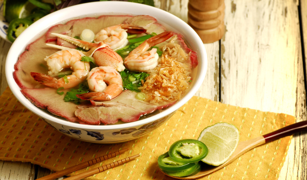 Тарелка супа с креветками и морепродуктами на столе