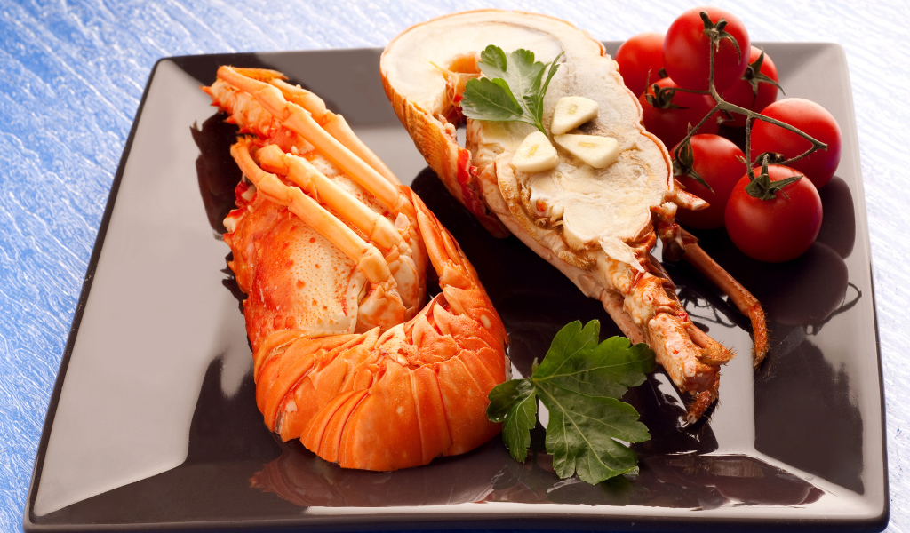 Аппетитный вареный омар на тарелке с помидорами 