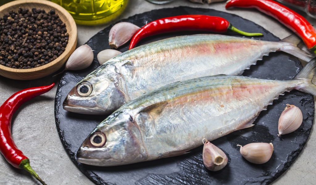 Свежая рыба на столе с красным перцем, чесноком и специями