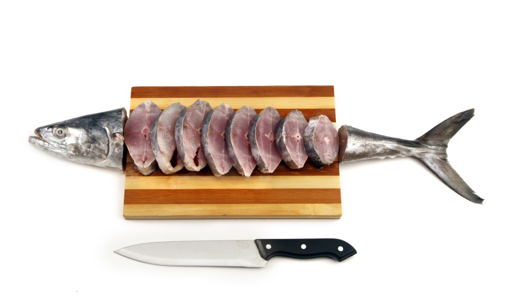 Свежая рыба кусочками на деревянной доске с ножом 