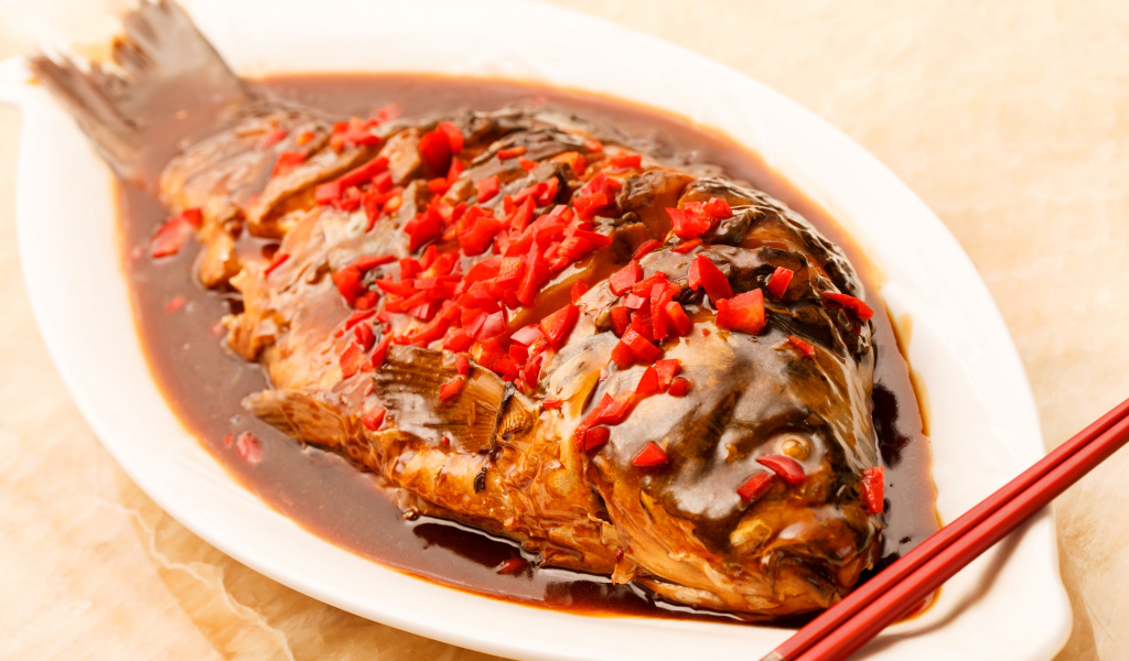 Жареная рыба с соусом и красным перцем в белом блюде