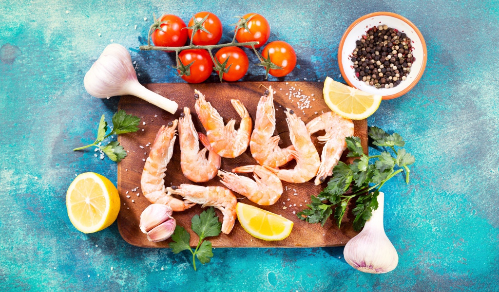 Креветки на разделочной доске с чесноком, лимоном и специями