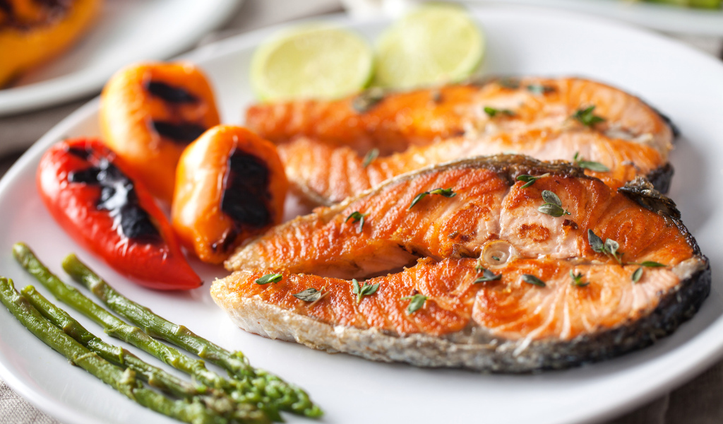 Два кусочка жареной красной рыбы с овощами 