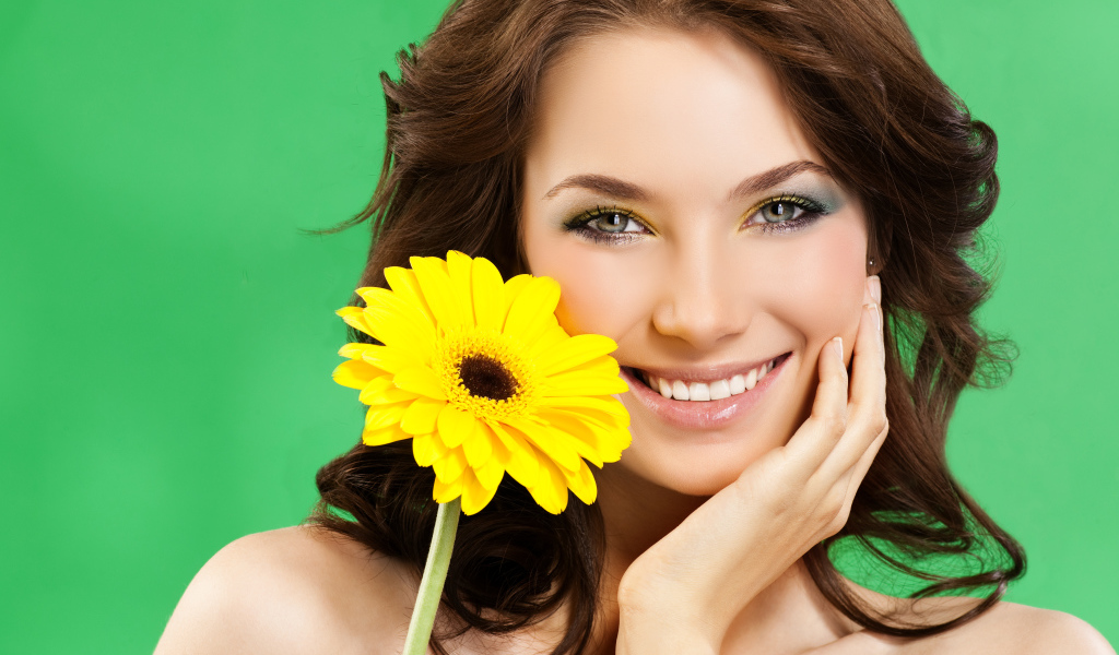 Девушка с красивой улыбкой и цветком желтой герберы в руках