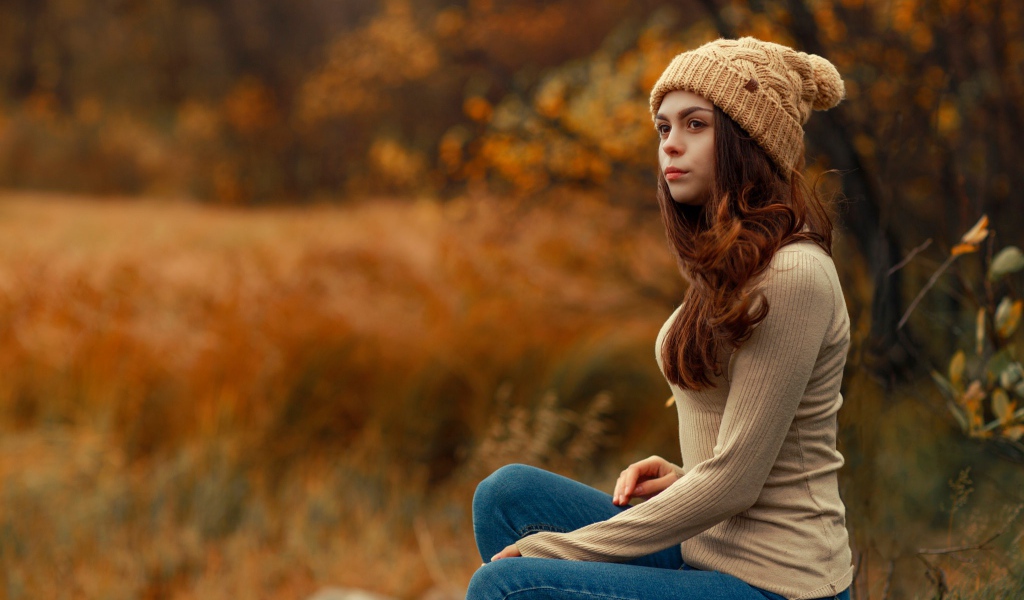 Молодая девушка в синих джинсах и теплой шапке