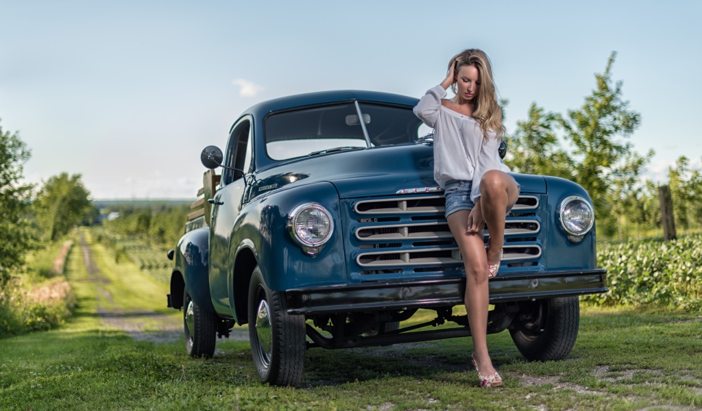 Молодая девушка стоит рядом с зеленым автомобилем Studebaker Pickup, 1953 года