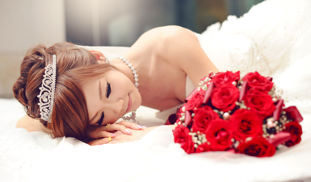 Красивая девушка азиатка в свадебном платье с букетом красных роз