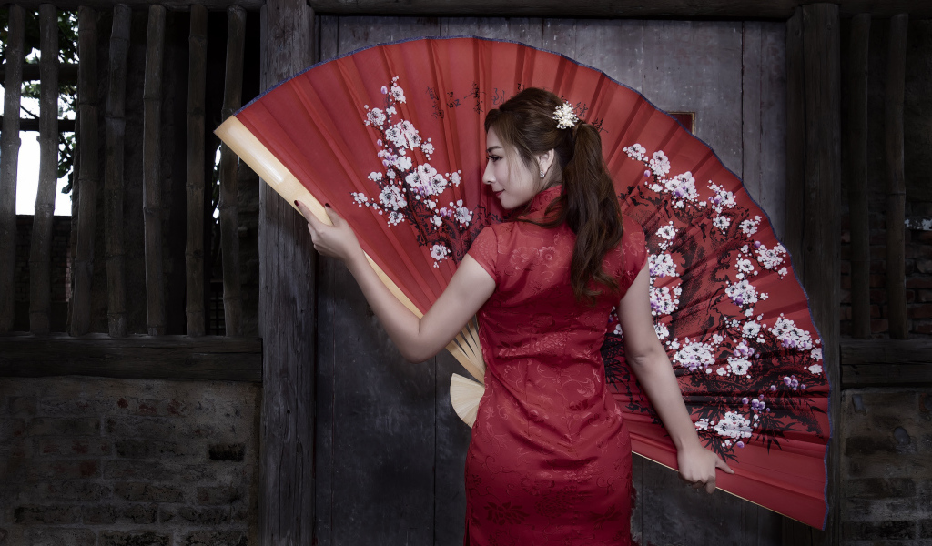 Красивая девушка азиатка в красном платье с большим веером