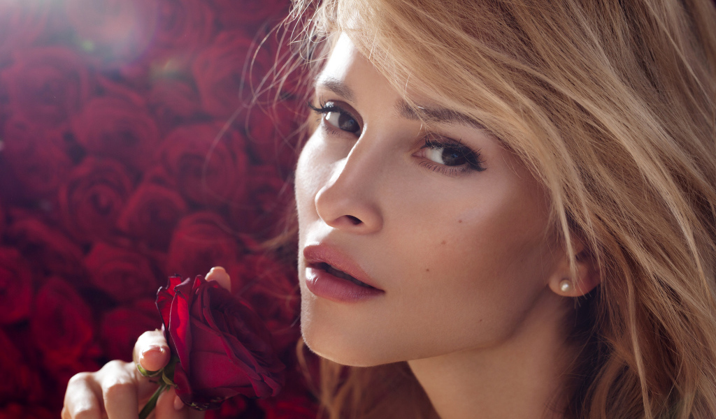 Красивая девушка блондинка с красной розой в руке