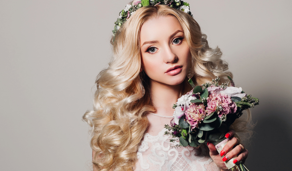 Красивая блондинка в свадебном платье с букетом цветов на сером фоне