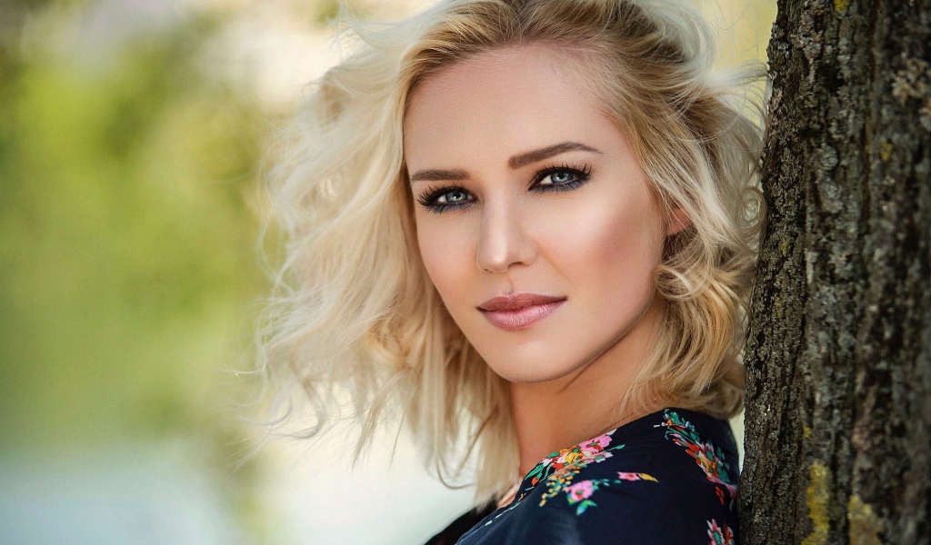 Красивая блондинка с голубыми глазами у дерева 