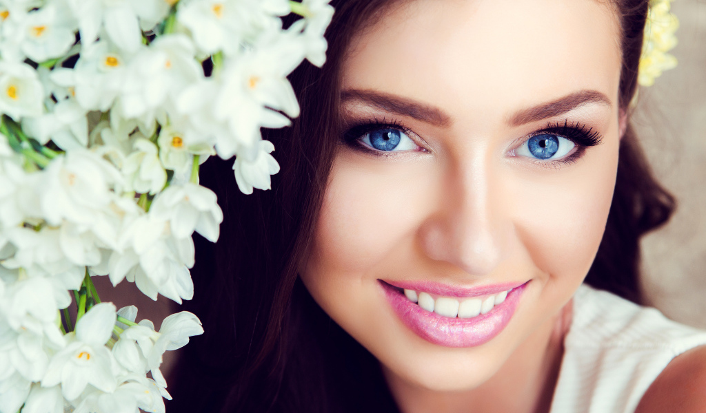 Красивая голубоглазая брюнетка с нежными цветами белой орхидеи