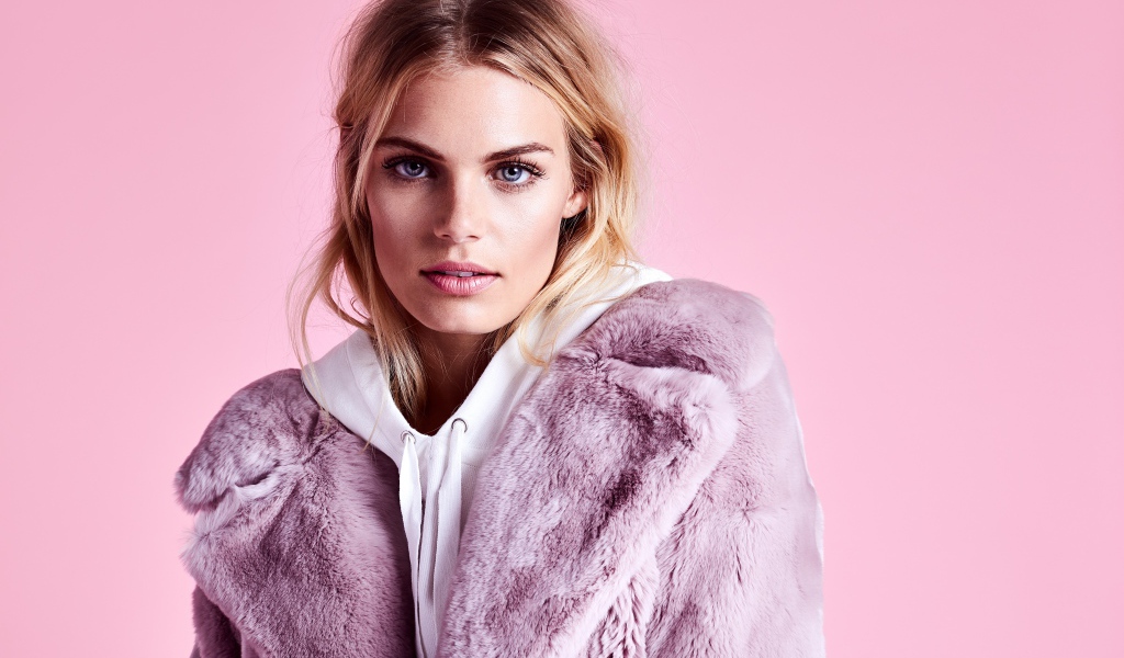 Красивая голубоглазая девушка в шубе на розовом фоне