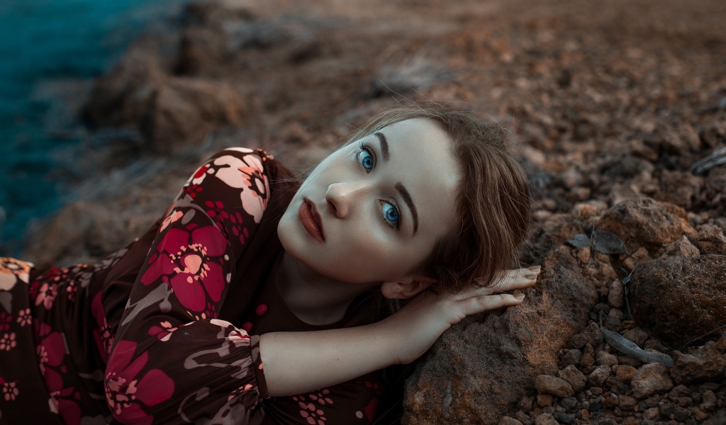 Красивая голубоглазая девушка лежит на камне 