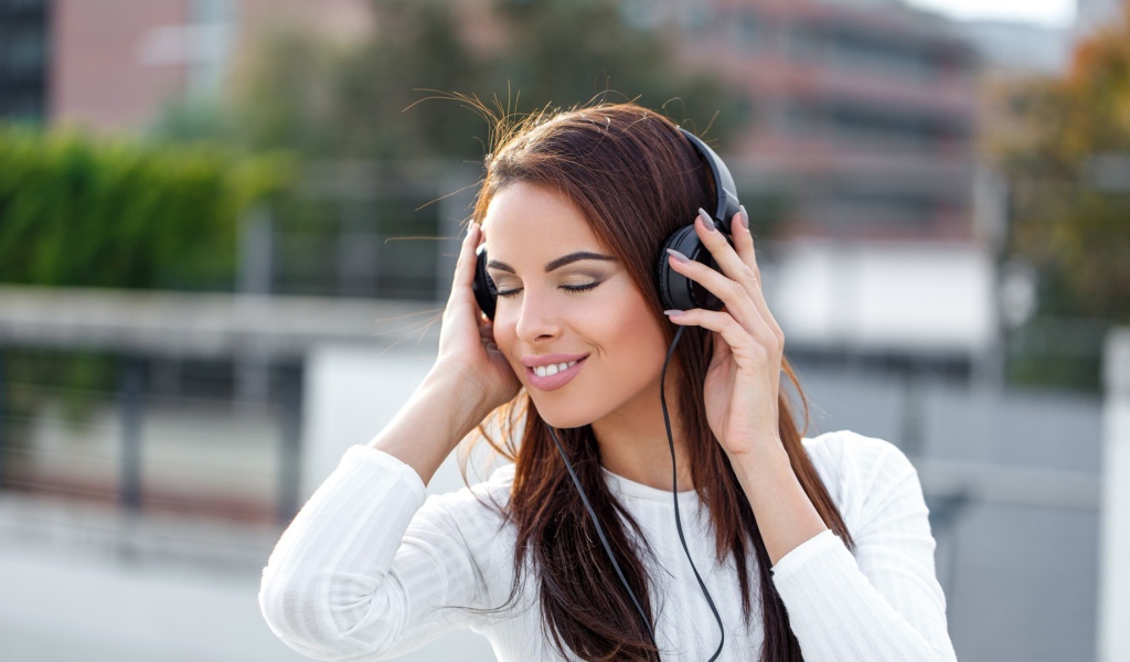 Красивая девушка брюнетка слушает музыку в наушниках 