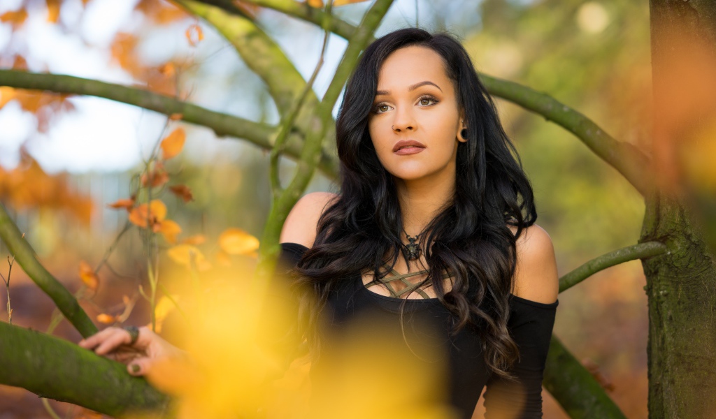 Красивая брюнетка у дерева в черном платье