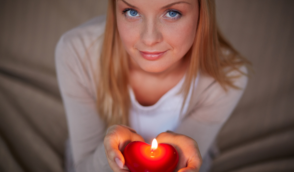 Красивая девушка держит в руках свечу в форме сердца