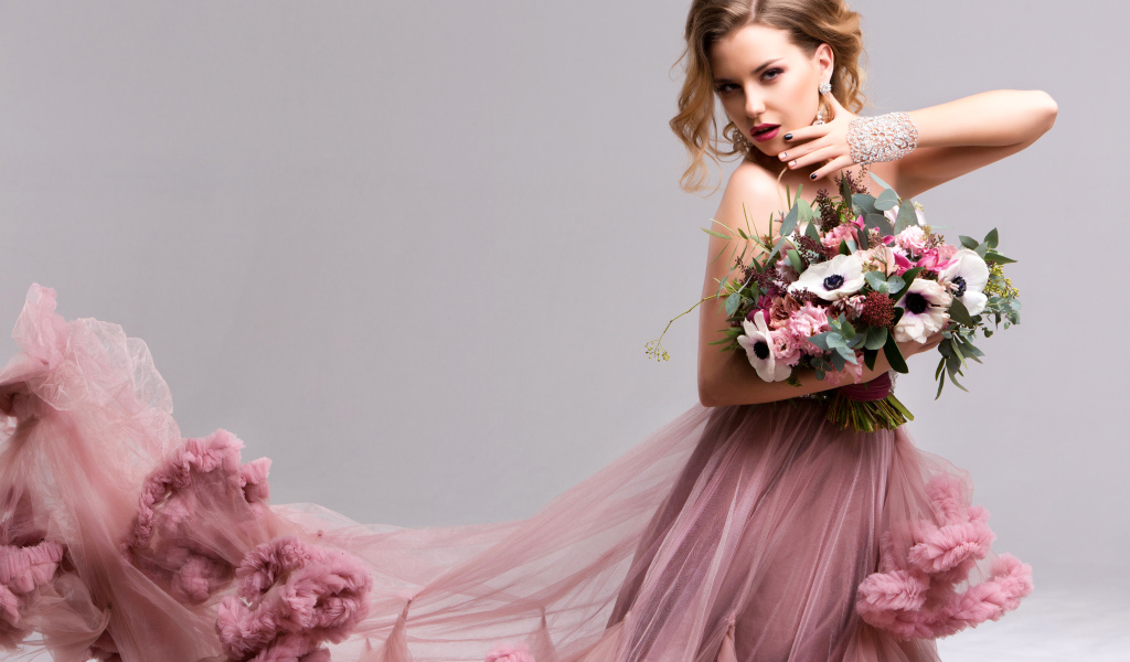 Эффектная девушка в красивом розовом платье с букетом цветов в руках