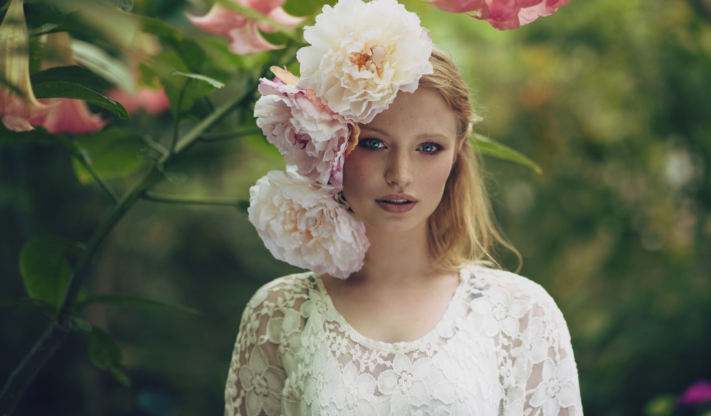 Красивая девушка в белом платье с большими пионами в волосах 