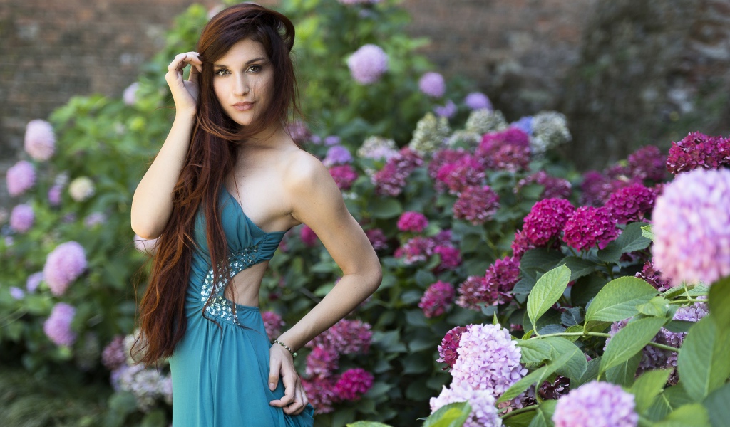 Красивая девушка модель в зеленом платье рядом с цветами гортензии