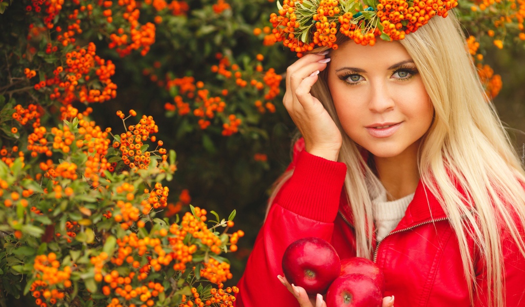 Красивая девушка с венком из рябины на голове и с красными яблоками в руках 