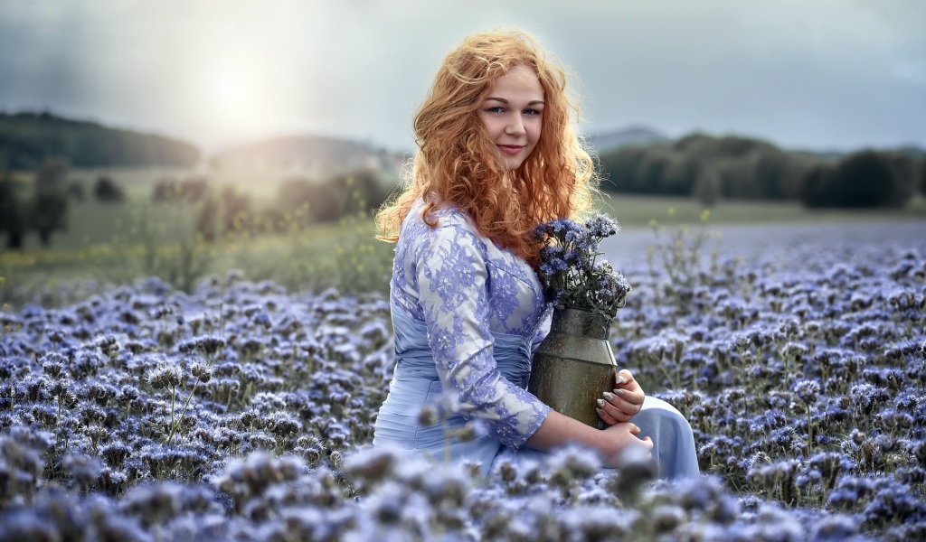 Красивая рыжеволосая девушка собирает цветы