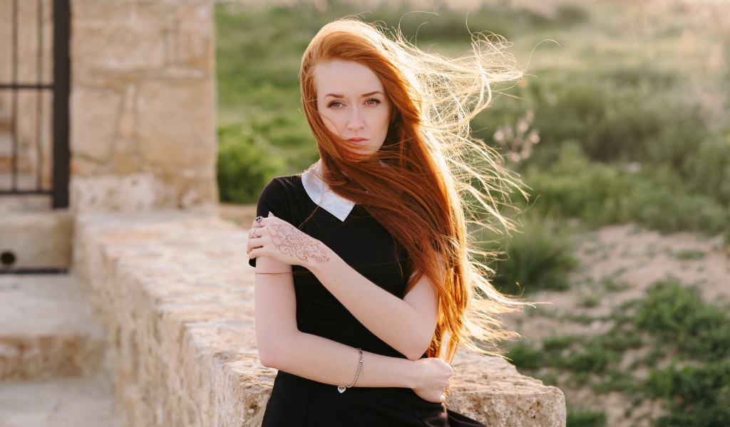Красивая рыжеволосая девушка в черном платье с рисунком на руке