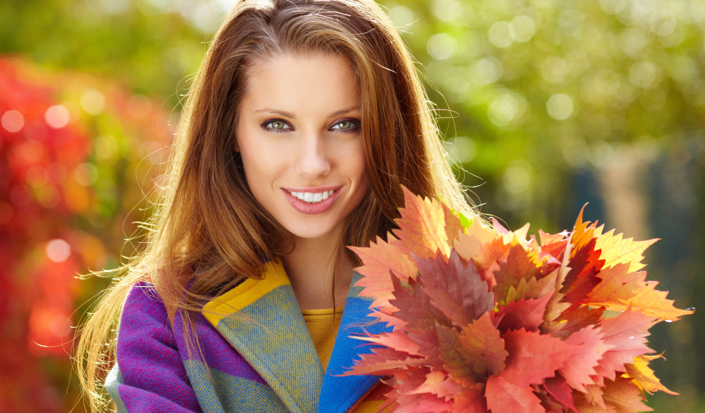 Красивая улыбающаяся девушка с букетом желтых листьев в руке