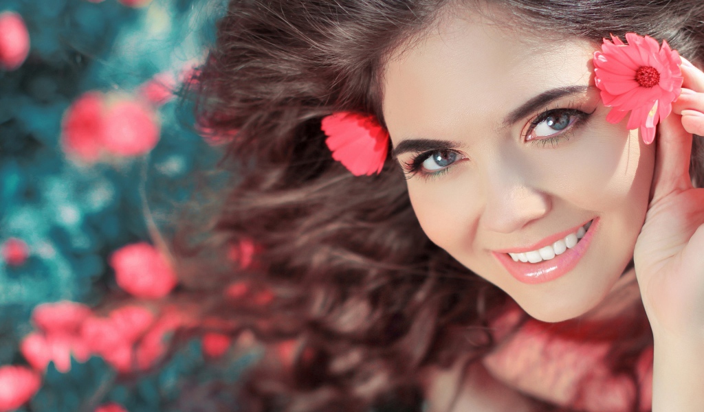 Красивая улыбающаяся девушка с розовыми цветами в волосах 
