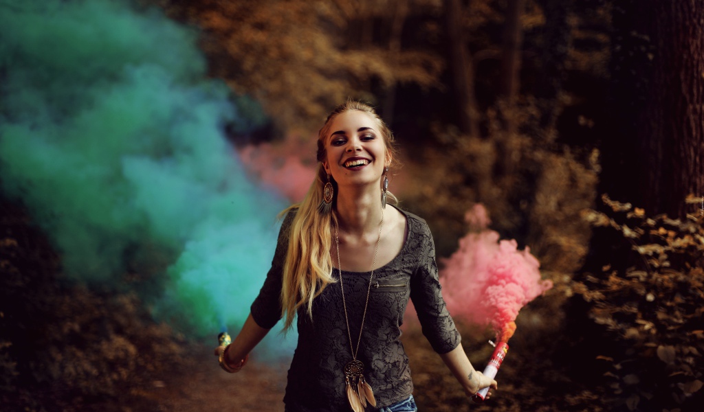 Красивая улыбающаяся девушка с дымовыми шашками в руках