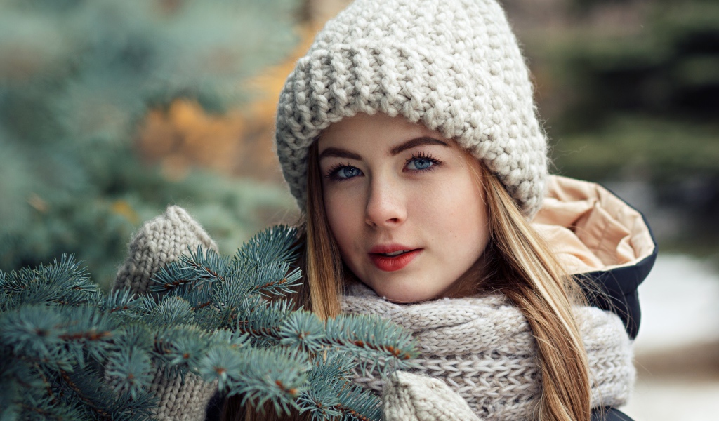 Красивая молодая голубоглазая девушка у еловой ветки зимой