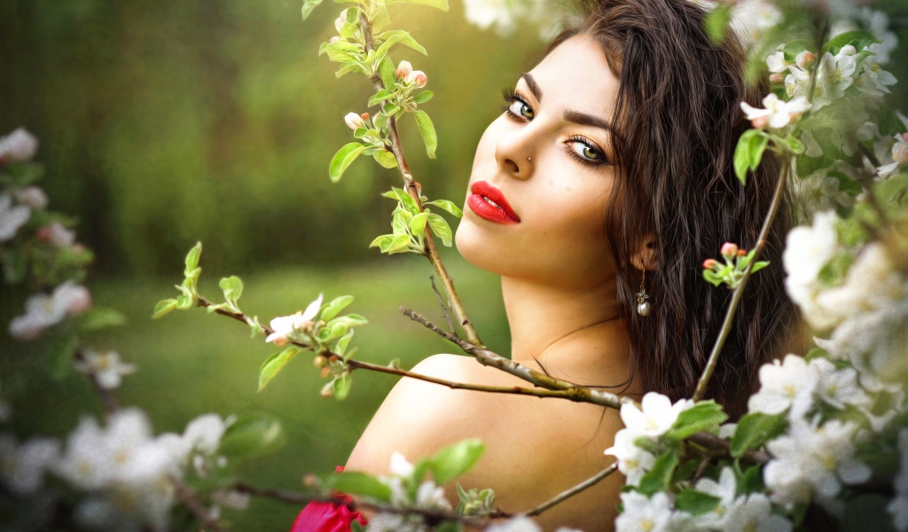 Красивая молодая девушка в ветках цветущей яблони 