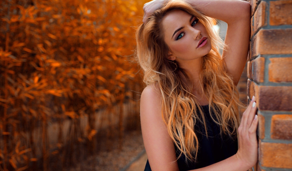 Голубоглазая девушка блондинка у стены 