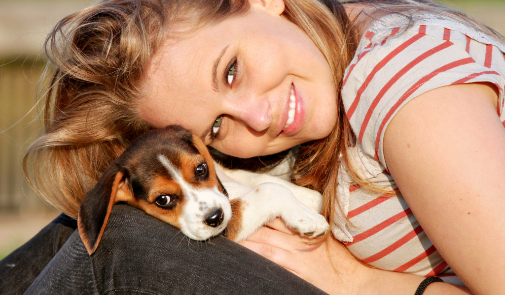 Убающаяся девушка шатенка с милым щенком на руках